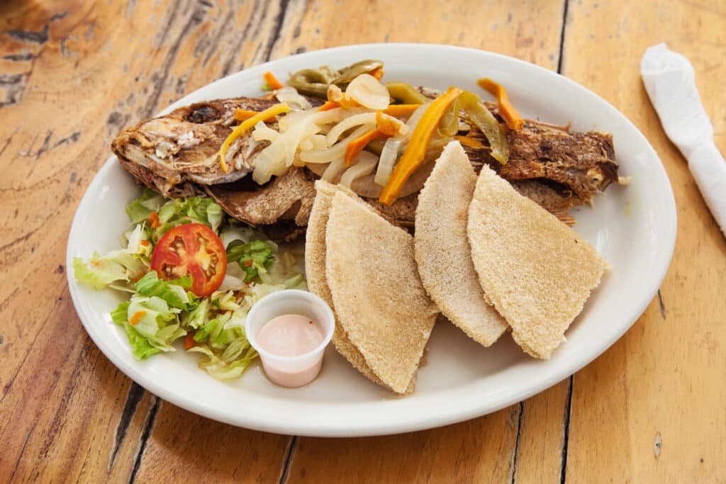 Whole fried fish with peppers, onions, and sides